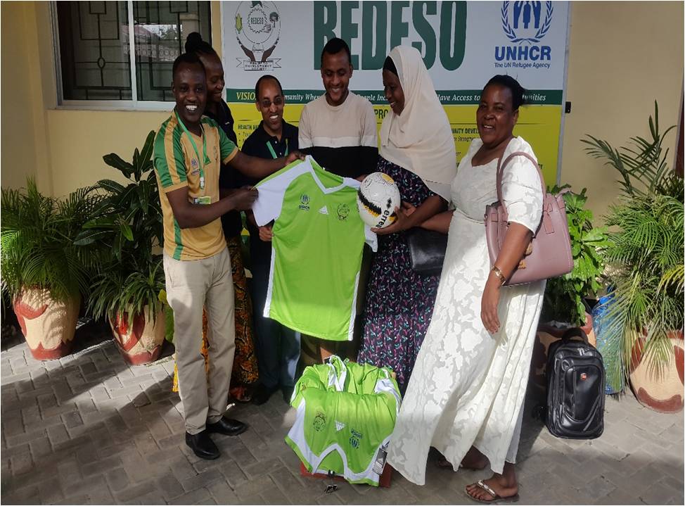 REDESO Senior ProgrammeManager, Senior Finance Manager, Program Officer, Host community team captain and local government leaders (Ms. TeclaMweyo and Ms. Mwamvita Polly) during handing over ofone set of football jersey and one football.